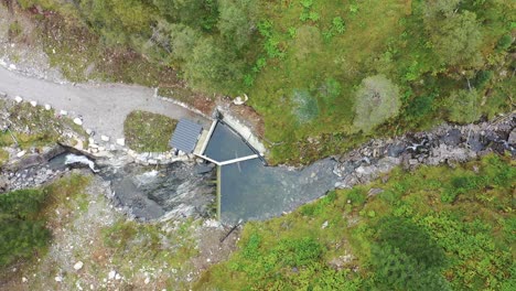 top down aerial view of small intake dam to hydroelectric river powerplant during drought and low water level - birdseye looking down and slowly moving right - markaani vaksdal norway