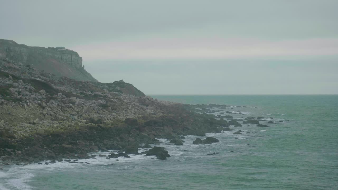 4K Cinematic landscape shot of the cliffs of Portland, Dorset, by the sea on Chesil Beach on a cloudy day