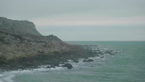 4k cinematic landscape shot of the cliffs of portland, dorset, by the sea on chesil beach on a cloudy day