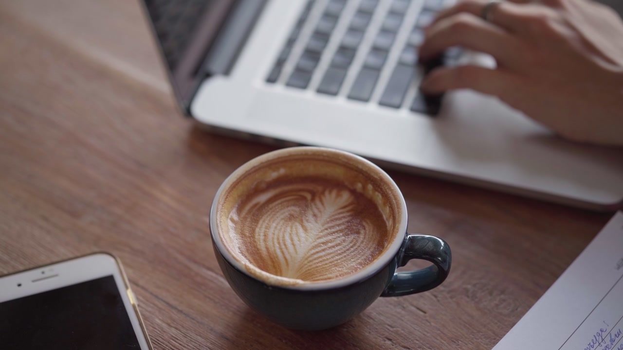 Pessoa trabalhando no laptop com café na mesa.