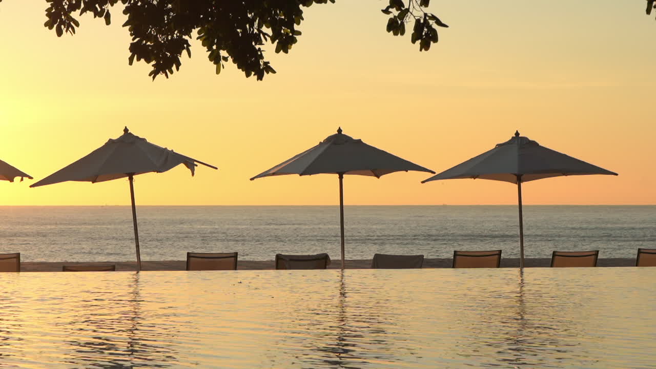 Peaceful seaside view with a few umbrellas near the ocean during a sunset with golden sky