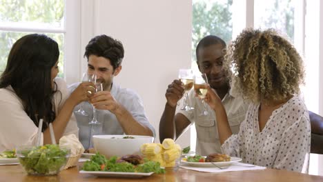 two happy couple toasting wine glasses while having meal