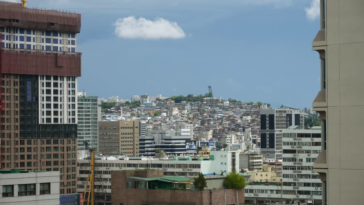 toma amplia entre rascacielos que muestra un distrito denso ubicado en una colina en la ciudad de seúl durante el cielo azul
