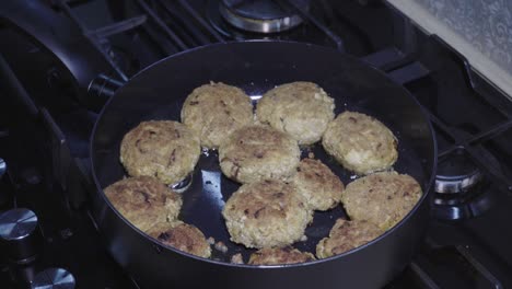 Pequeñas-Chuletas-De-Tofu-Bellamente-Fritas-Se-Fríen-En-La-Sartén,-La-Cámara-Se-Mueve-A-Lo-Largo-De-La-Sartén