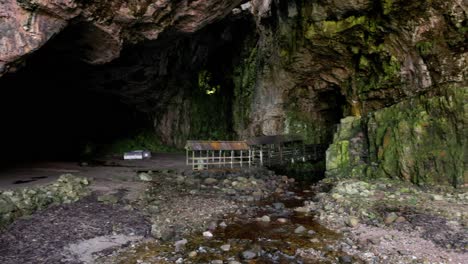 revealing the opening of smoo cave and walking platform leading to the waterfall