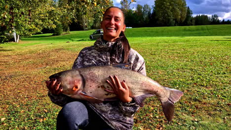 big catch, smiling woman holding a large fish in cesis, latvia's outdoor setting