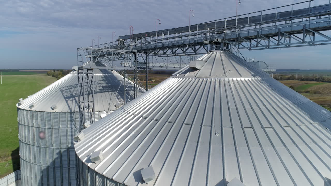 Tops of grain elevators. Modern silver granaries for grain storing and processing. Exterior of aluminum containers at sunlight. View from the air.