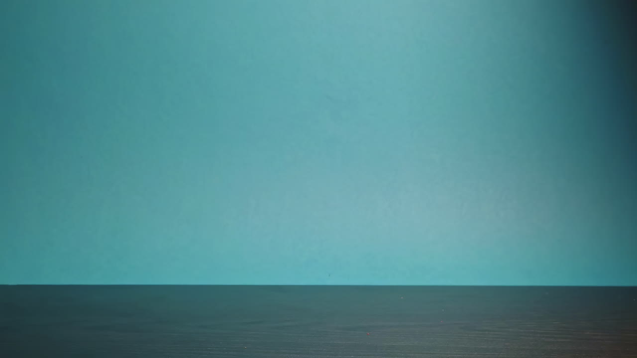 Scenic slowmotion shot of moving tomato on the desk in front of a blue background