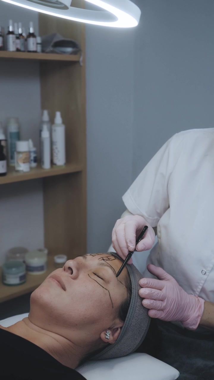 Specialista in estetica che delinea le sopracciglia per la procedura di microblading