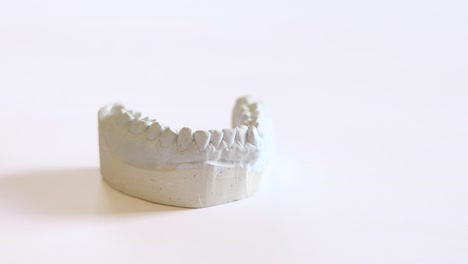 A dentist picks up and then places down a dental impression, for making invisible braces, bruxism, or dentures, with his hand in a blue medical glove