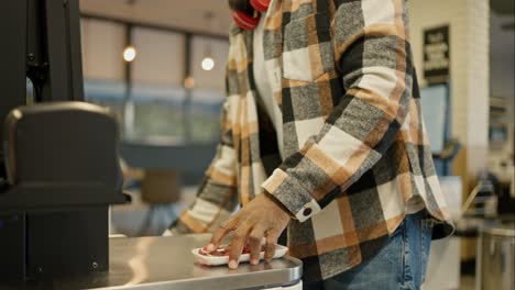 Close-up-shot-of-a-Black-man-in-a-checkered-shirt-scanning-the-goods-he-needs-at-a-self-service-checkout-in-a-modern-supermarket