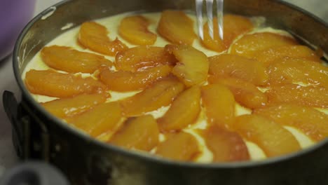 putting pieces of peaches on mixed cottage cheese and chicken eggs. cheesecake