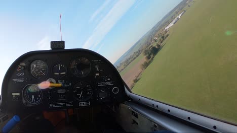 pilot's point of view from a cockpit of a sailplane flying low above fields