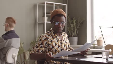 hipster black man in wheelchair doing paperwork in office