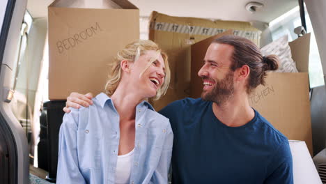 Portrait-Of-Couple-Sitting-In-Back-Of-Removal-Truck-On-Moving-Day