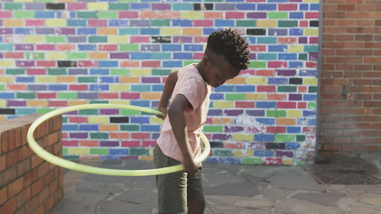 Ragazzo che gioca con gli hula hoop, si diverte in un'attività all'aperto nel cortile della scuola.