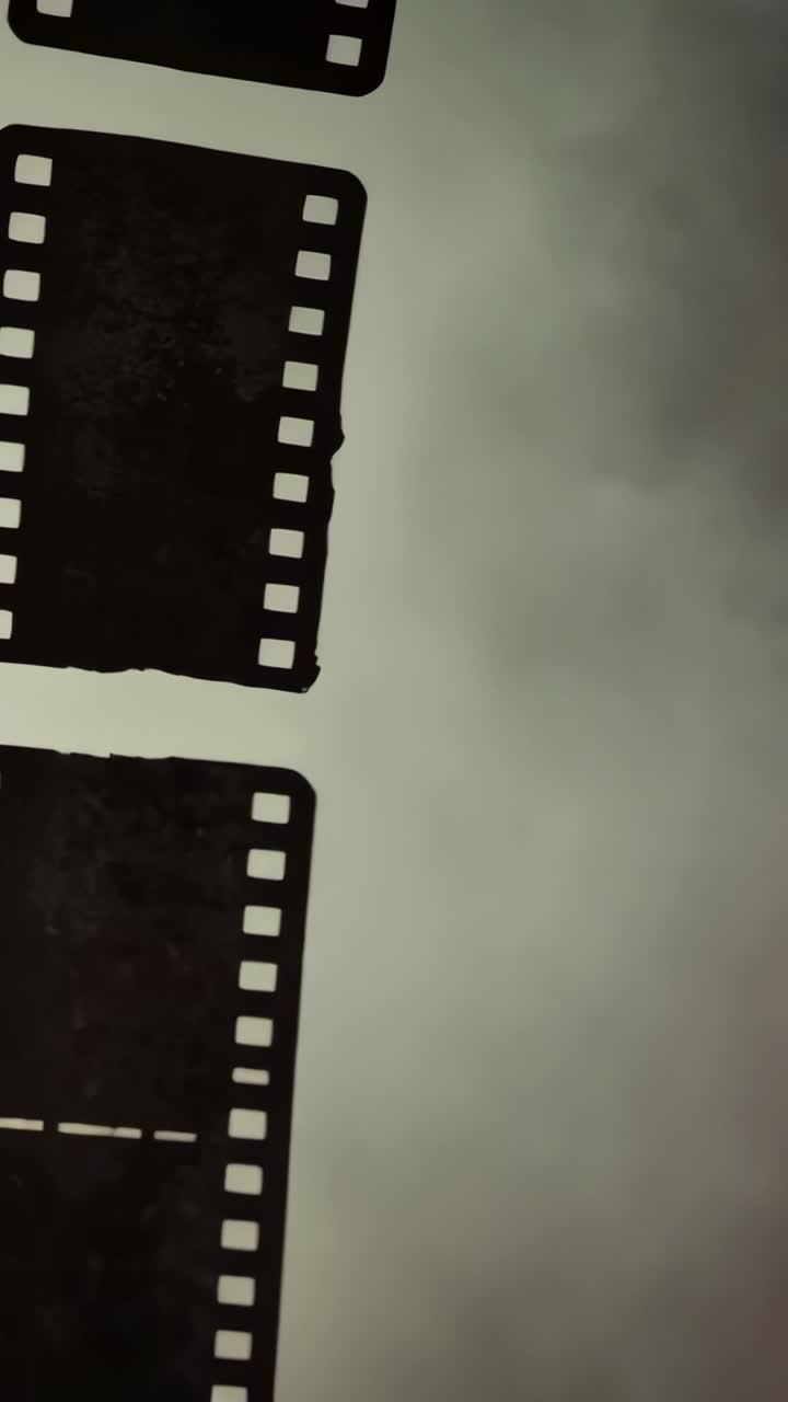 Vertical video: Lowering offframe hand sliding perforated filmstrip over cloudy sky, copy space