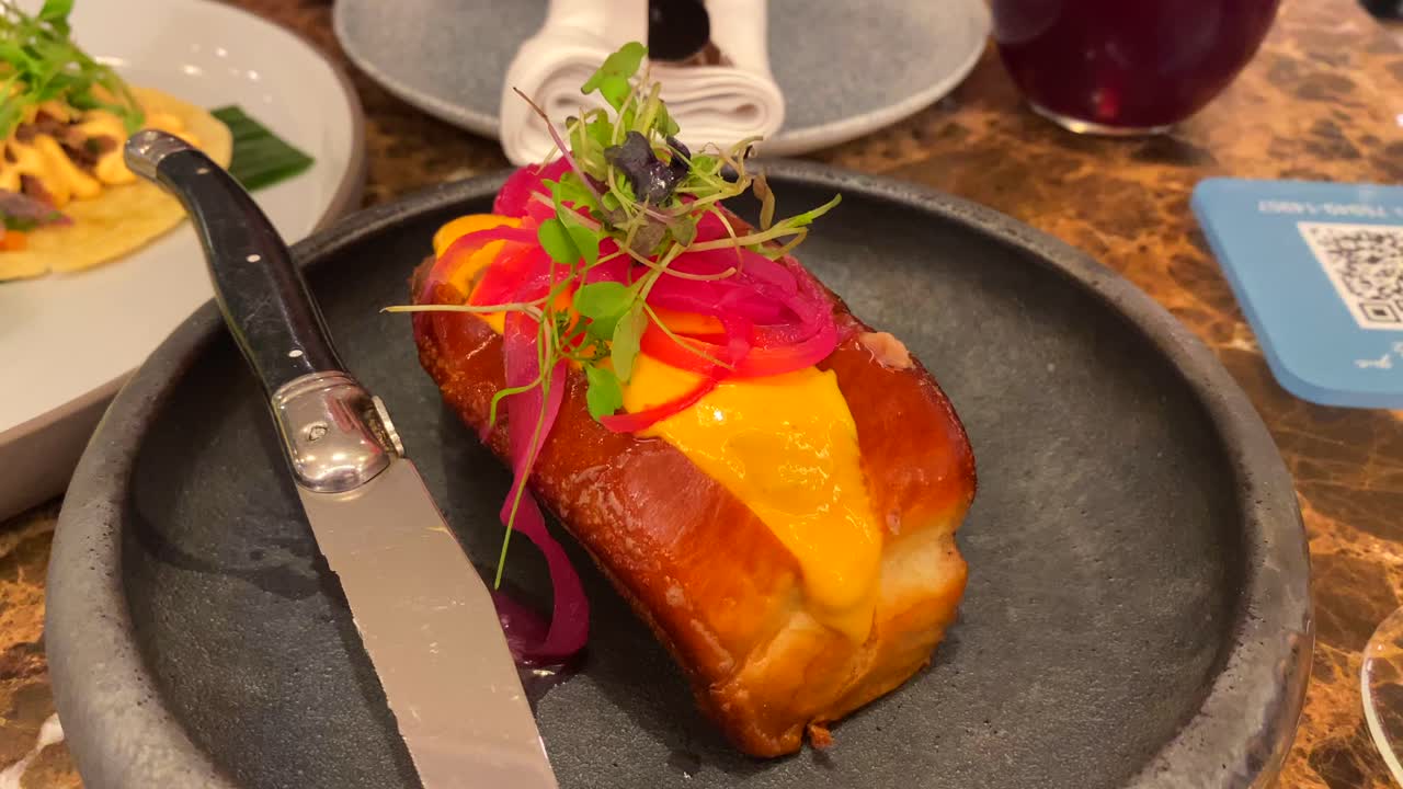 pan de brioche suave lleno de carne deliciosa, cebollas rojas en escabeche, salsa amarilla y microgreens, comida deliciosa en un plato, restaurante de lujo, tiro de 4k
