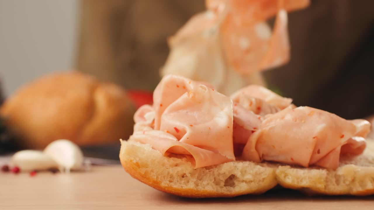 Mortadella ham sandwich, Traditional italian focaccia filled with thin pesto slices of mortadella, served by chef man in cafe restaurant. Macro of traditional italian spanish tapas antipasti.