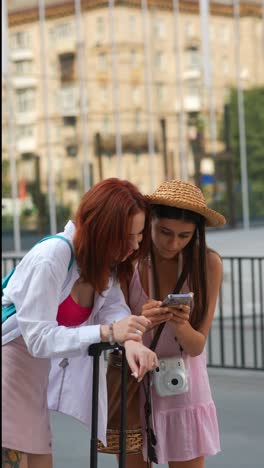 two women looking at a phone in a city