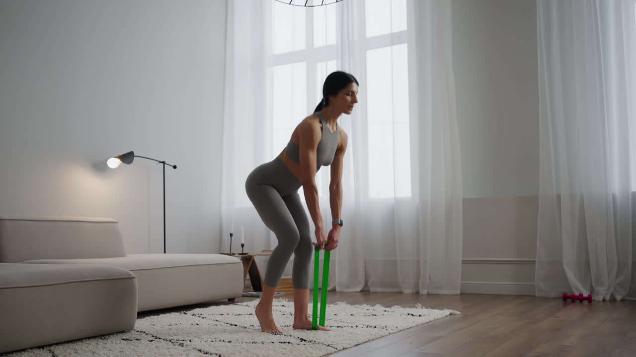 mujer realizando sentadillas con banda de resistencia en casa