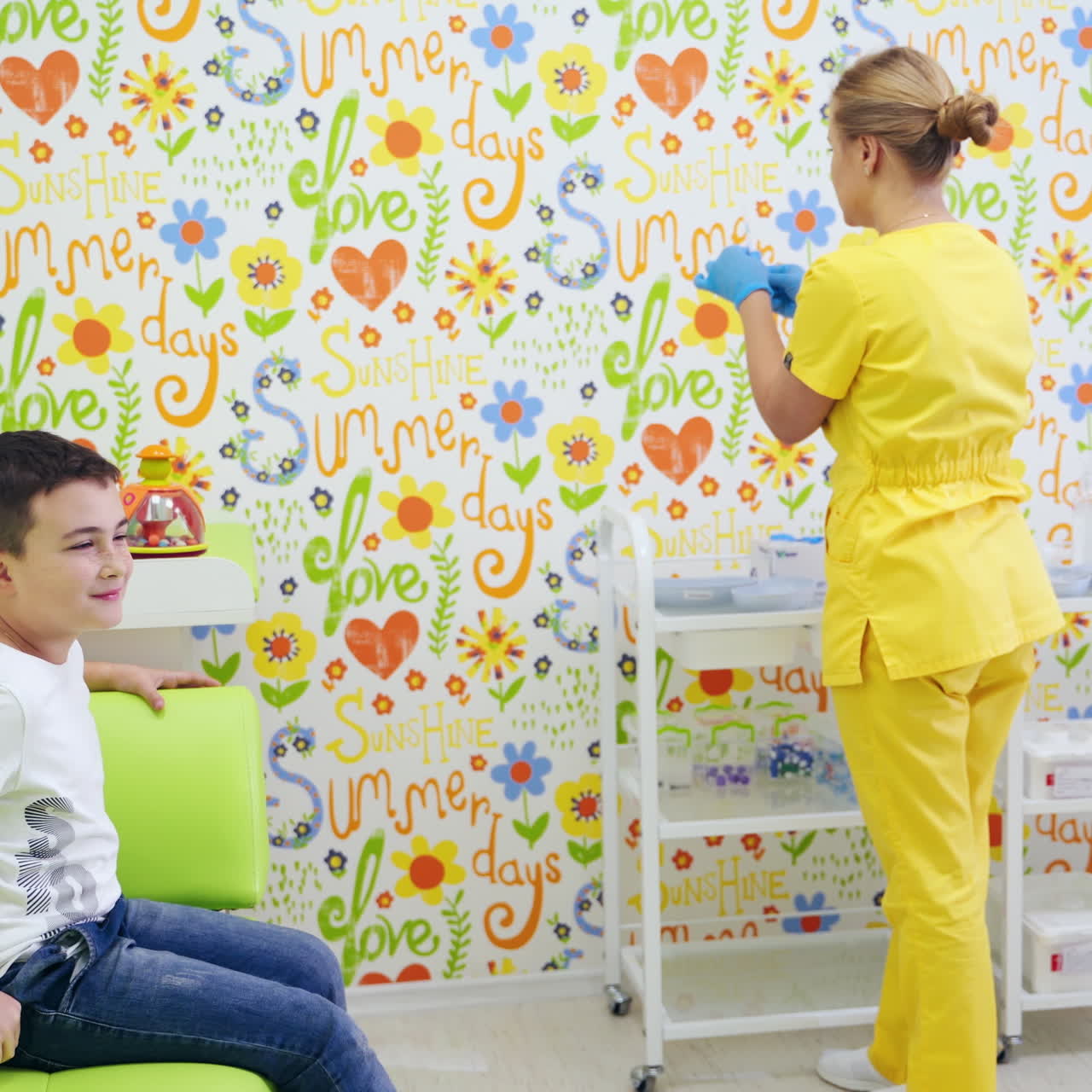 Female doctor and child in the medical room. Nurse in yellow uniform prepares syringe for injection. Happy boy sitting in the armchair in clinic. Health care concept.