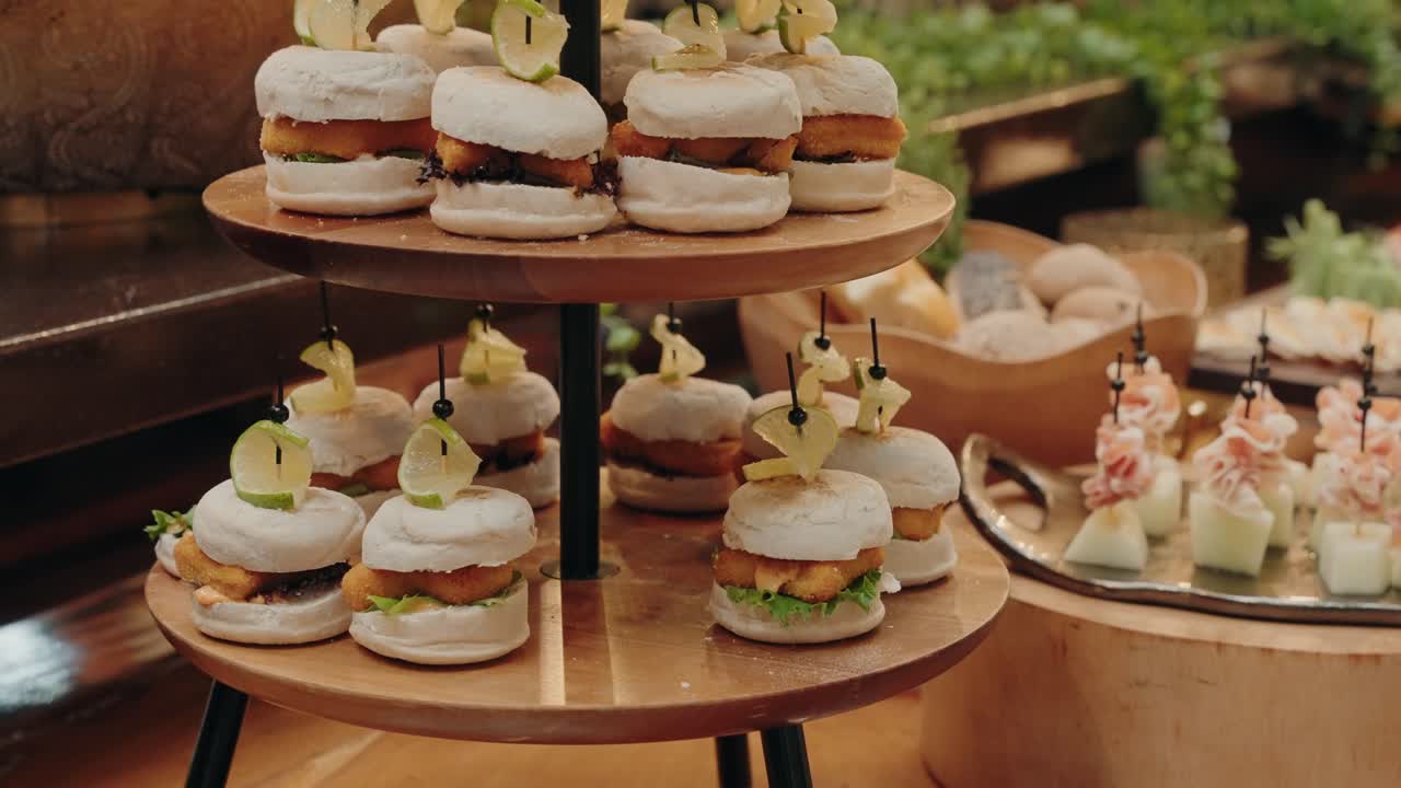 small gourmet burgers stacked on wooden trays with skewers and fruit garnish