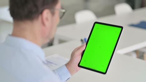 hombre de mediana edad usando una tableta con pantalla de croma verde