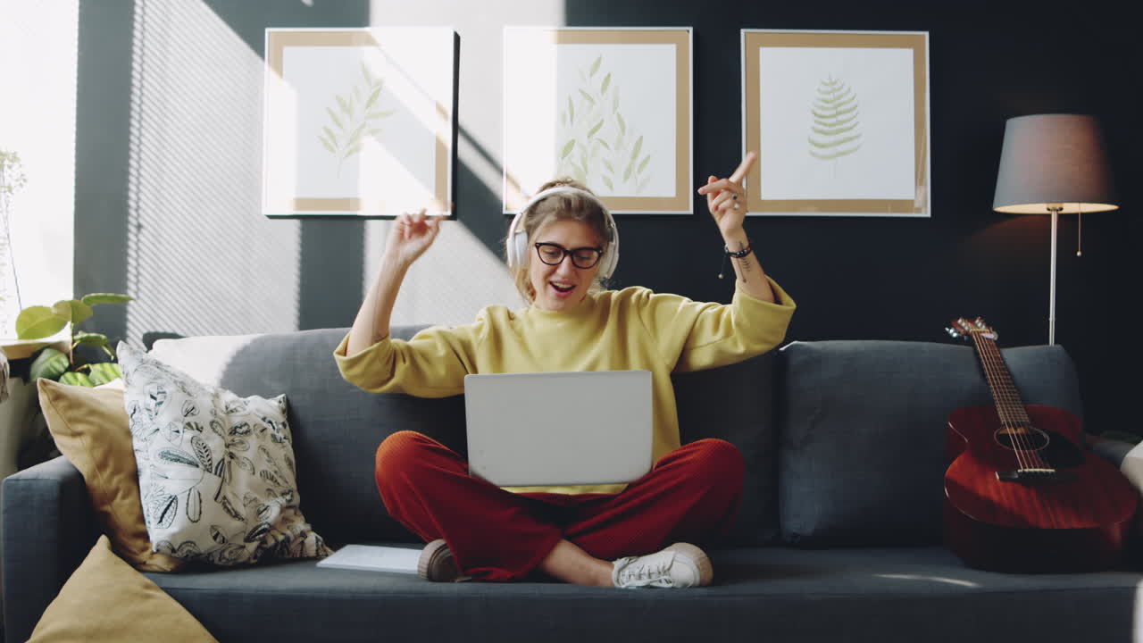 mujer con auriculares escuchando música en una computadora portátil en casa
