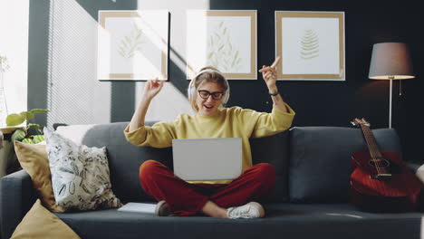 woman in headphones listening to music on laptop at home