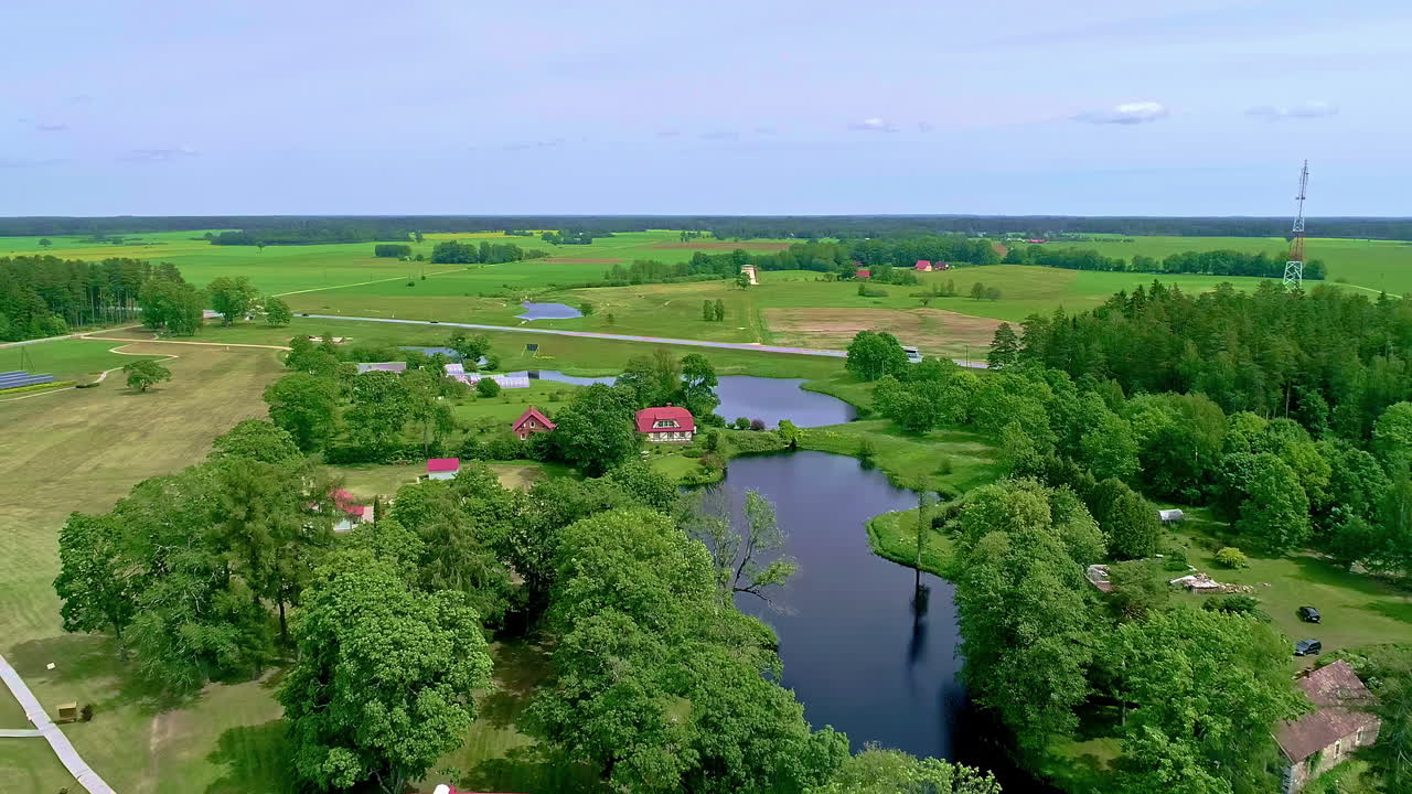공중 드론은  ⁇ 은 날에 밀집한 녹색 식물로 둘러싸인 호수를 따라 시골 오두막 위에서 뒤로 이동  ⁇