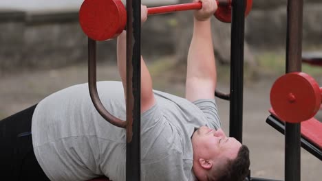 a large overweight man lifts a barbell lying down during sports sports and motivation a large overweight man lifts a barbell lying down during sports sports and motivation