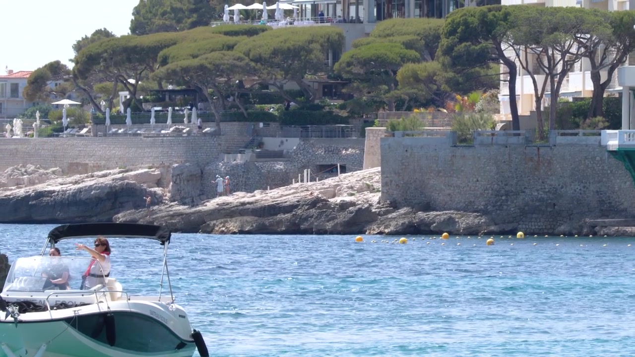 Un motoscafo attraversa le acque blu del Mediterraneo oltrepassando ville costiere bianche a Cassis, Francia