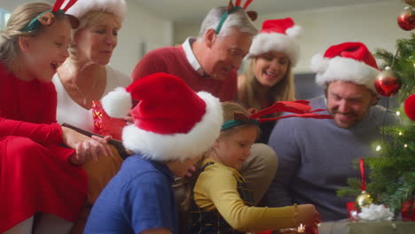 Multi-Generation-Family-Exchanging-And-Opening-Gifts-Around-Christmas-Tree-At-Home