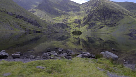 Revealing-tilt-up-shot-of-Lough-Callee,-lake-and-a-Mcgillycuddy-Reeks-mountain-on-a-wonderful-sunny-day-in-Ireland-in-4K