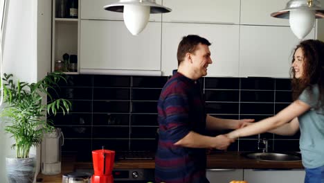 una joven pareja alegre y atractiva enamorada bailando juntos un baile funky en la cocina en casa en vacaciones