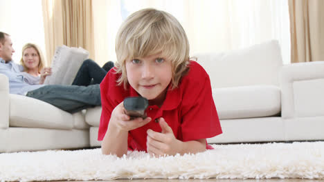 Kid-watching-television-on-floor-with-his-parents-on-sofa