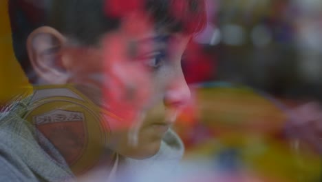 unique view through the glass of a boy's face while he plays arcade games with the lights flickering on his face