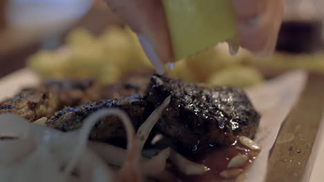 close up view of meal on the plate that woman waters lemon juice with potatoes onion