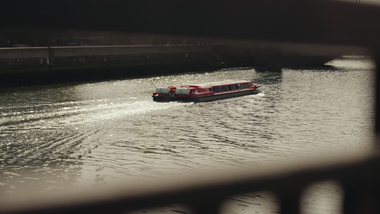 Modern red colored boat sailing and leaving behind water trails on a river in Dublin, Ireland. Water taxi