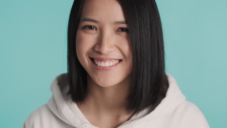 Asian-woman-in-sweater-smiling-on-camera.