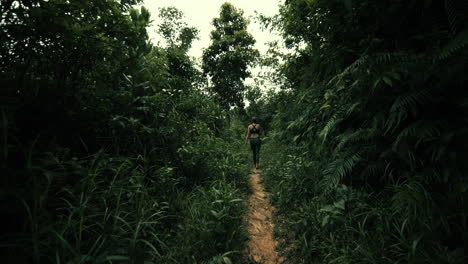 woman running through a lush jungle trail