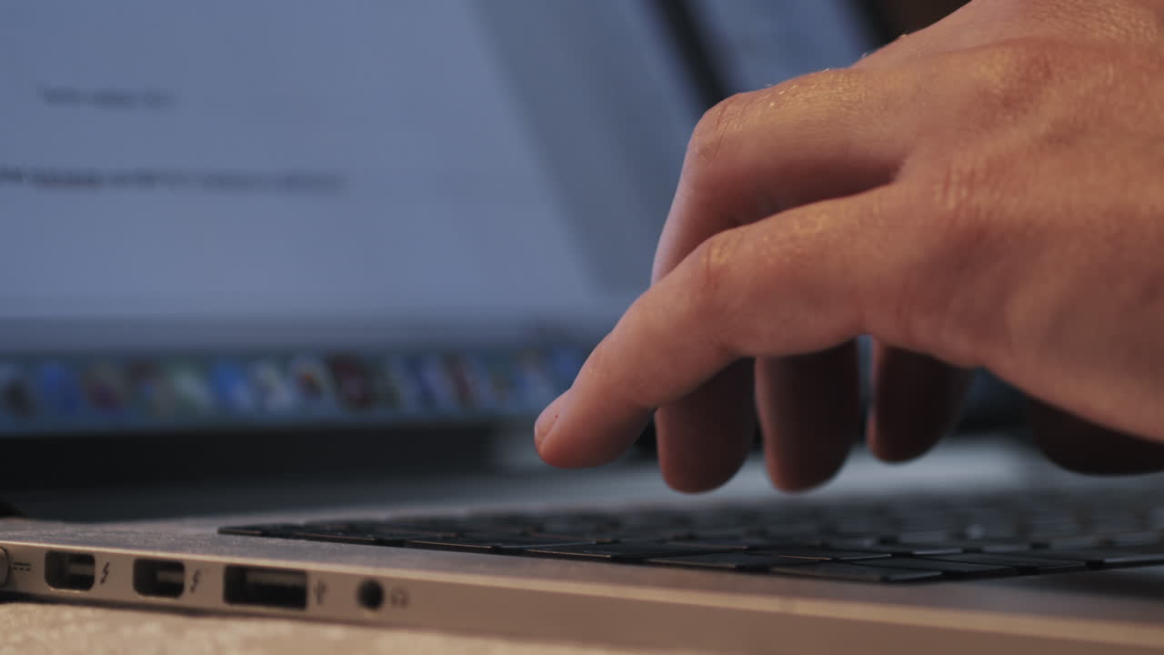 los dedos escriben en la computadora portátil mientras la pantalla abre los navegadores en segundo plano