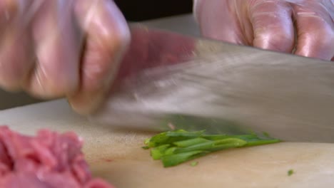 chef chopping spring onions in traditional chinese kitchen