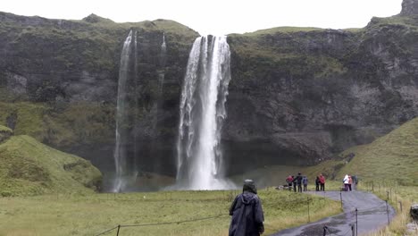 Traveler-walking-towards-waterfall-on-rainy-day