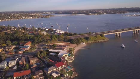 aerial view of waterfront houses with ocean view and many boats and a long bridge