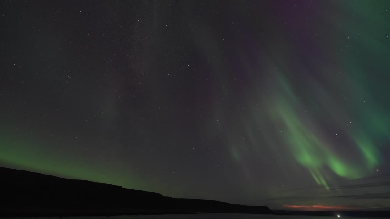 el cielo de invierno está iluminado por la hermosa danza de la aurora boreal sobre las oscuras aguas tranquilas del fiordo.