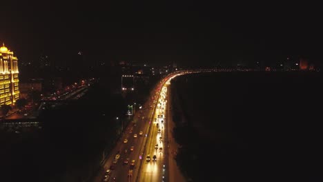 an aerial view with cinematic drone movement of the iconic marine drive nightlife with air india and trident hotel buildings in sight.