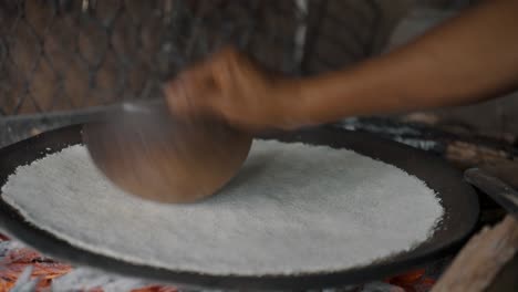 making tortilla de yuca in ecuador - hand spreading and pressing dough evenly in circular shape