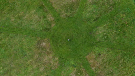 aerial descending birds eye view of a person standing in a circle with rays formed by freshly mown grass